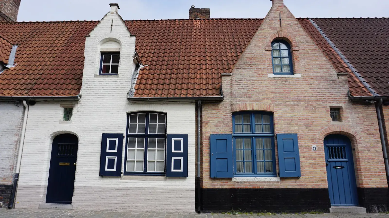 Rij bakstenen woonhuizen met blauwe raamluiken