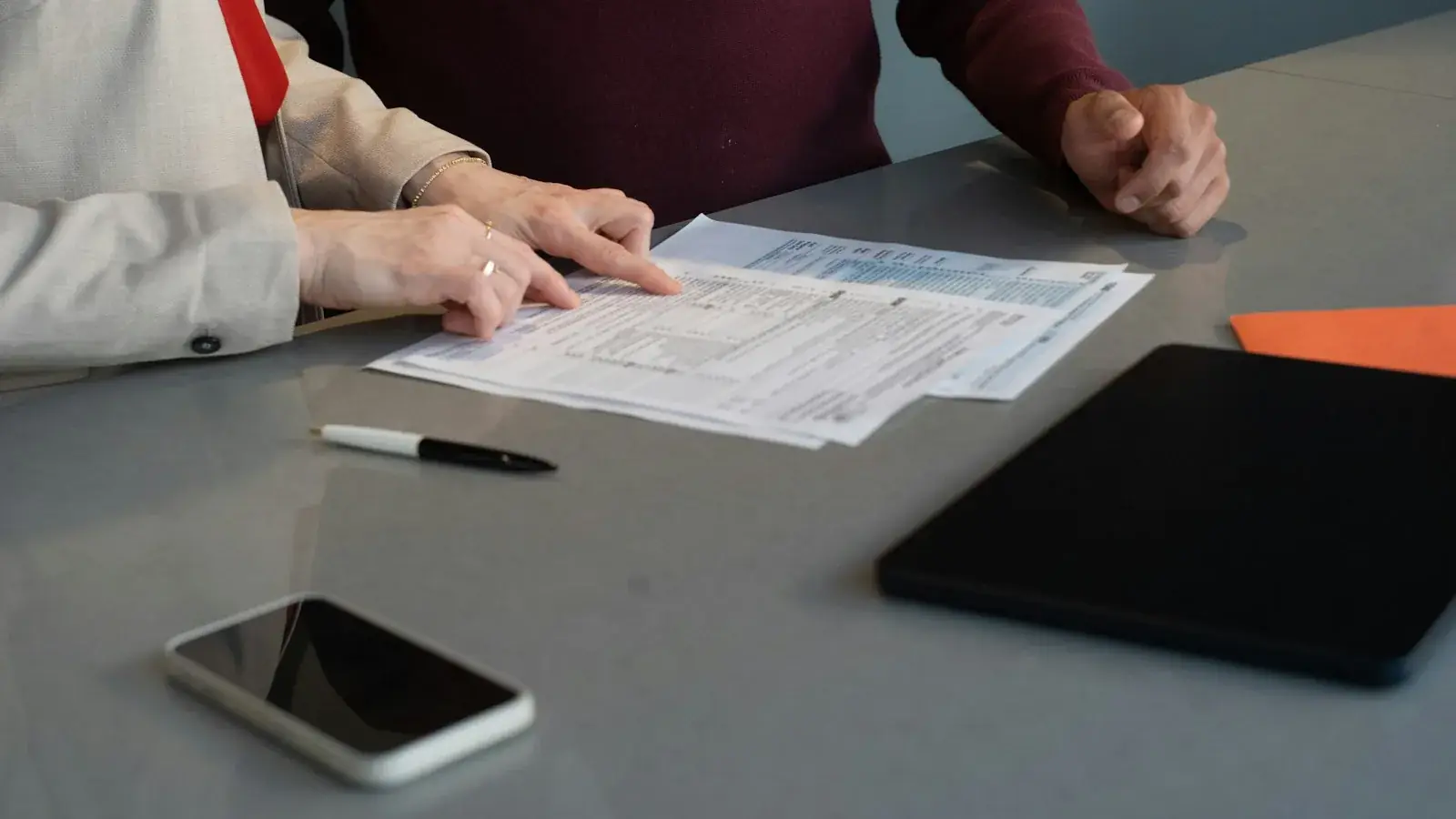 Twee mensen die samen een document met een verkoopdossier doornemen