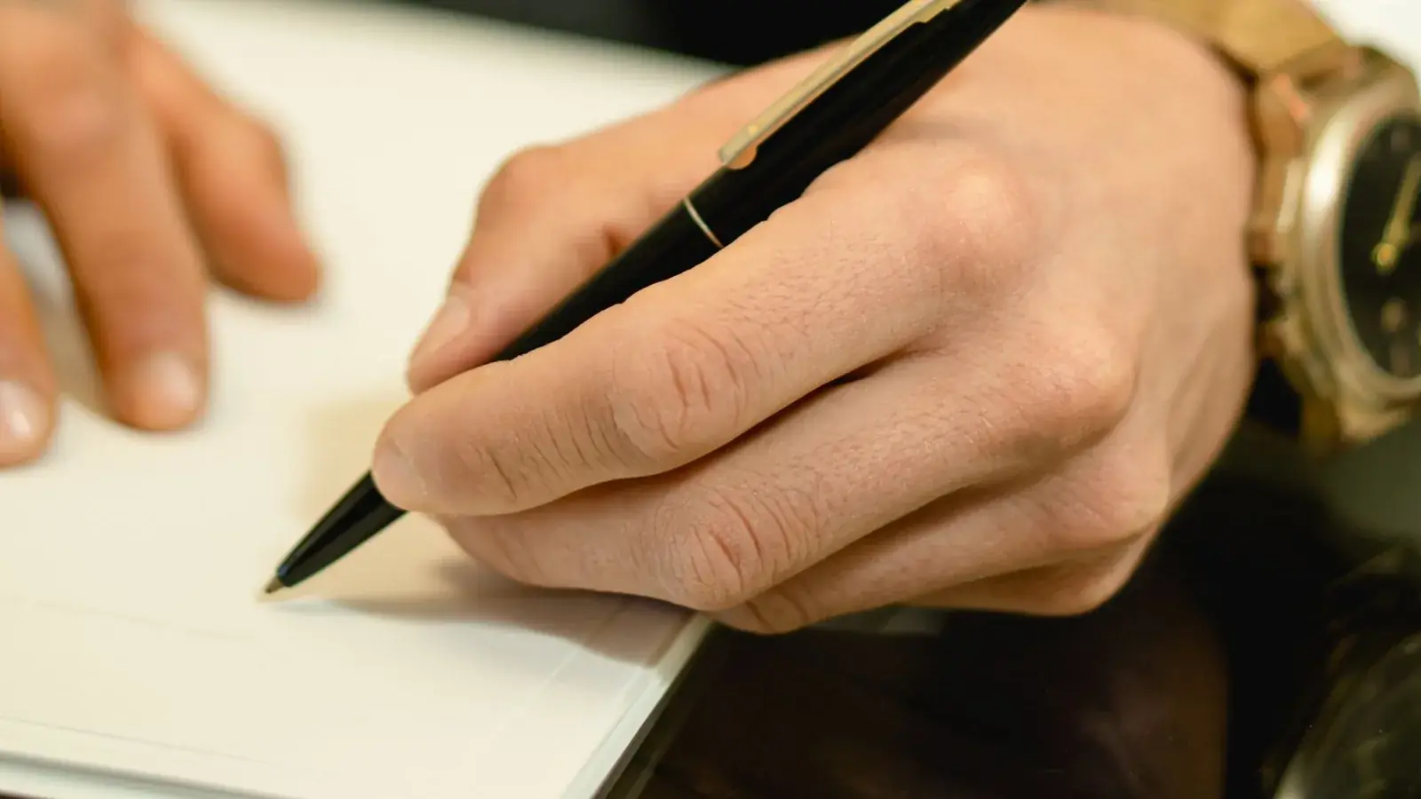 Close-up van een hand die met een pen een document ondertekent