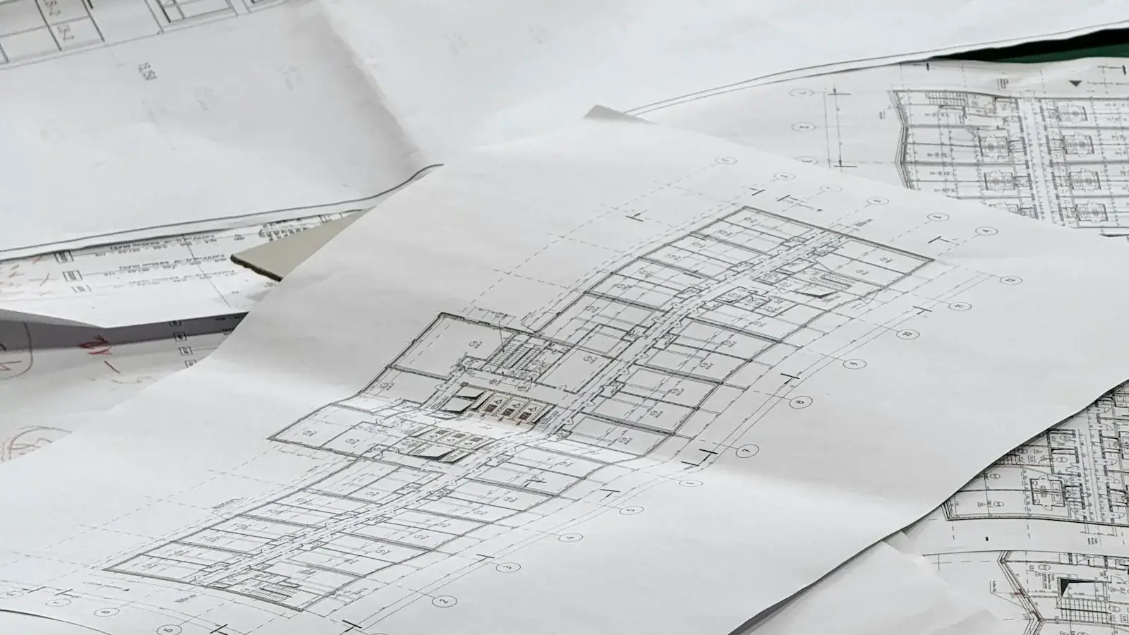 Opengevouwen bouwplannen en plattegronden op een tafel
